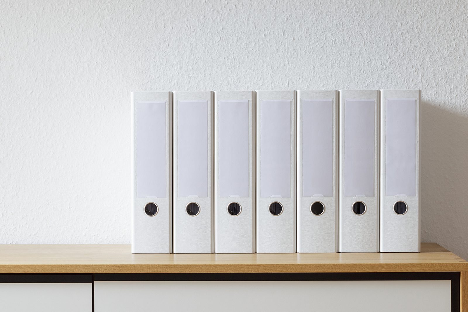 Rows of white document binders on an office shelf